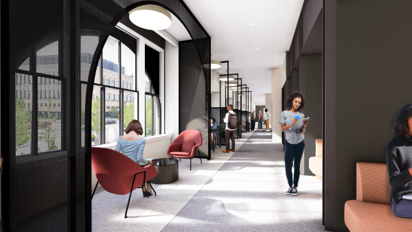 Collaborative workspace hallway with seating areas and people working near large windows.